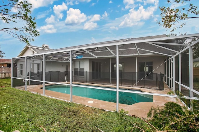 rear view of property featuring a fenced in pool, a patio area, a lawn, and glass enclosure