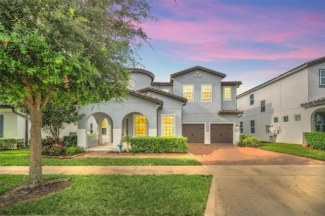 mediterranean / spanish home featuring a lawn and a garage