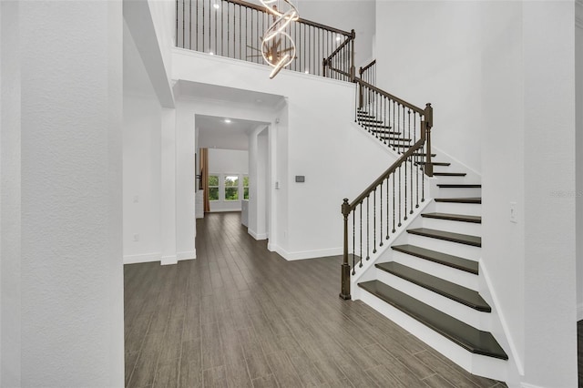 foyer entrance featuring a towering ceiling and dark wood-type flooring