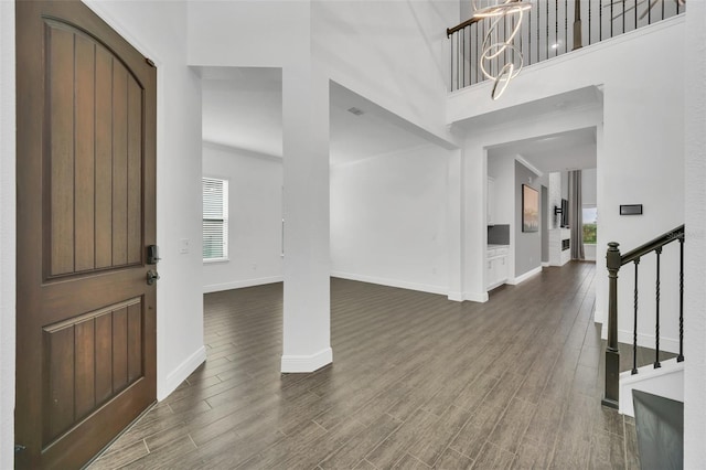 entrance foyer with an inviting chandelier, a wealth of natural light, a high ceiling, and dark hardwood / wood-style floors