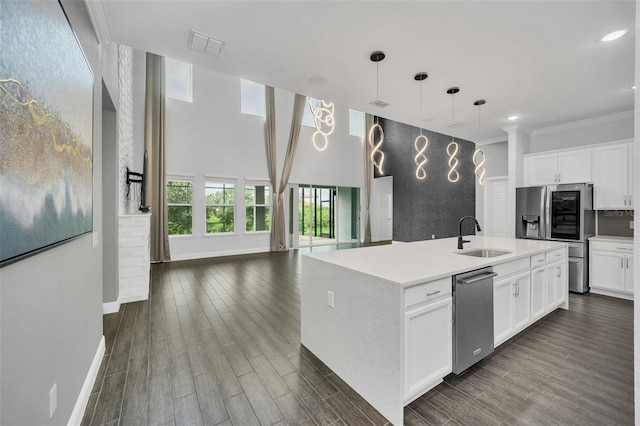 kitchen featuring hanging light fixtures, a center island with sink, white cabinetry, and sink