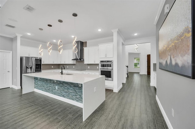 kitchen featuring an island with sink, stainless steel appliances, dark wood-type flooring, and white cabinetry