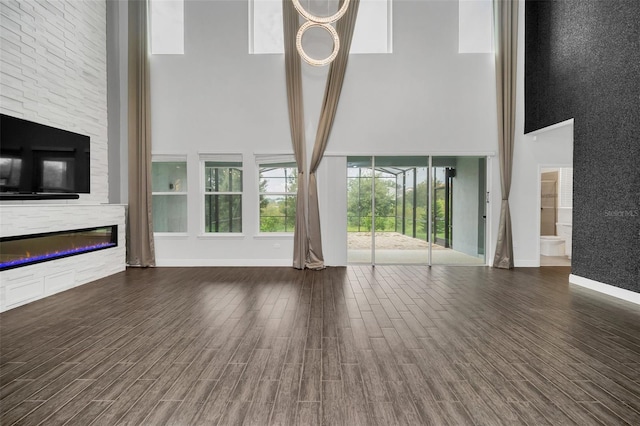 unfurnished living room featuring a high ceiling, beam ceiling, dark hardwood / wood-style flooring, and a wealth of natural light