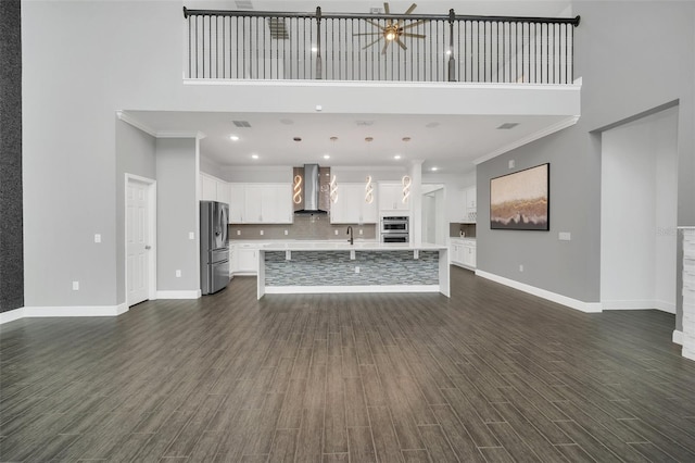 unfurnished living room with crown molding, a high ceiling, dark hardwood / wood-style floors, and ceiling fan