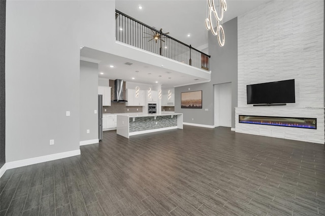 unfurnished living room with a stone fireplace, a high ceiling, and dark wood-type flooring