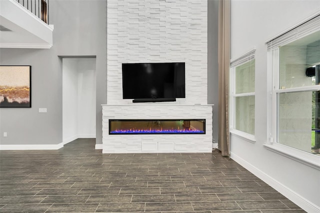 unfurnished living room featuring a high ceiling, dark hardwood / wood-style floors, and a fireplace