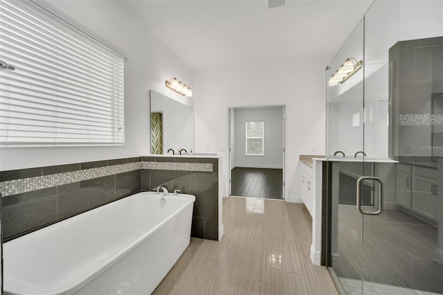 bathroom featuring tile walls, vanity, and shower with separate bathtub