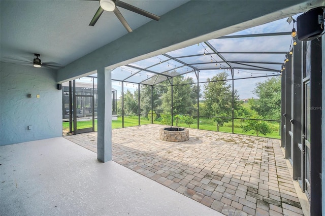 view of patio with a lanai, ceiling fan, and an outdoor fire pit