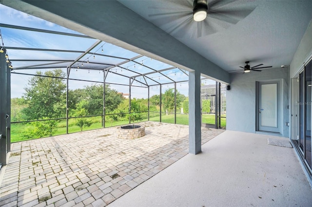 view of patio / terrace featuring ceiling fan, a fire pit, and glass enclosure