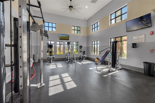 exercise room with ceiling fan and a high ceiling