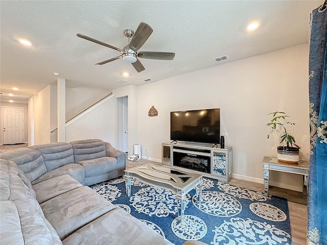 living room with ceiling fan, a textured ceiling, and wood-type flooring