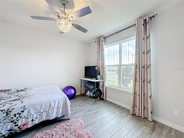 bedroom with ceiling fan, a textured ceiling, and light hardwood / wood-style flooring