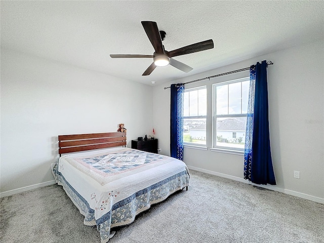 bedroom with ceiling fan, carpet floors, and a textured ceiling