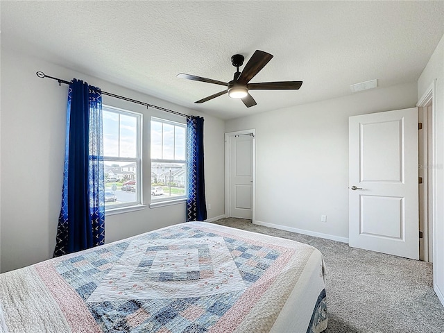 carpeted bedroom with ceiling fan and a textured ceiling