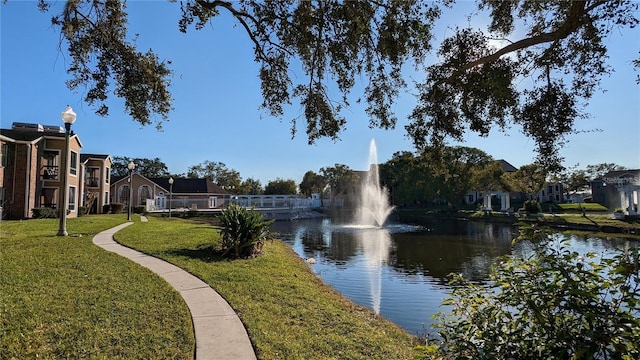 view of home's community with a water view and a lawn