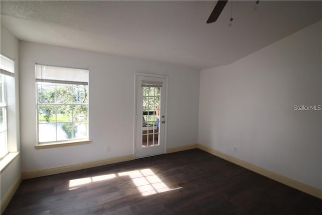 unfurnished room with dark wood-type flooring, ceiling fan, and a healthy amount of sunlight