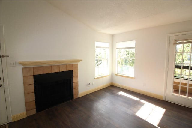 unfurnished living room with a textured ceiling, a tiled fireplace, and dark wood-type flooring