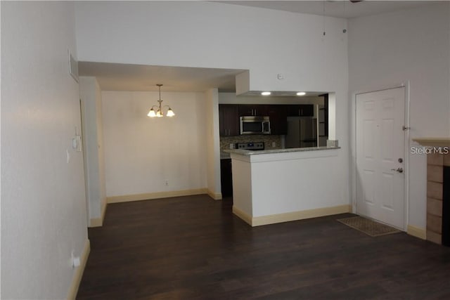 kitchen featuring dark wood-type flooring, stainless steel appliances, dark brown cabinets, and a high ceiling