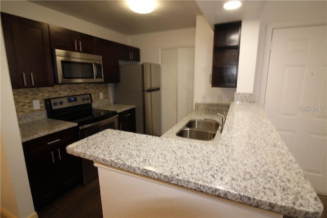 4400 Thornbriar Ln Unit A202, Orlando, FL 32822 - kitchen featuring stainless steel appliances, a peninsula, a sink, dark brown cabinets, and tasteful backsplash