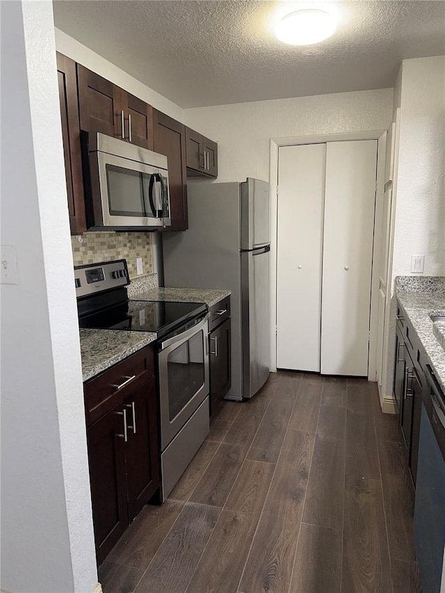 kitchen with decorative backsplash, a textured ceiling, light stone countertops, dark wood-type flooring, and stainless steel appliances