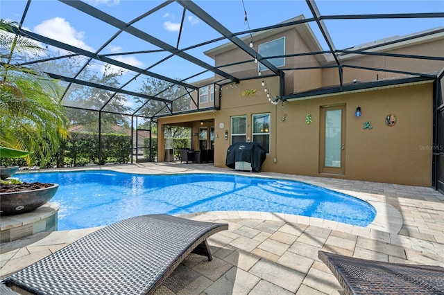 view of pool with glass enclosure and a patio area