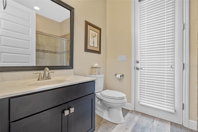 bathroom featuring wood-type flooring, vanity, toilet, and a shower with door