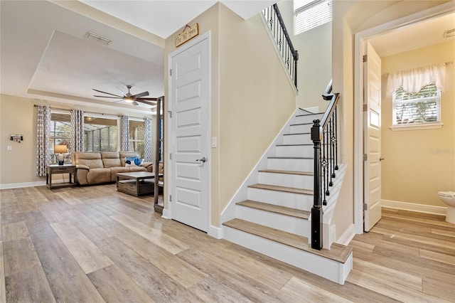 staircase featuring a wealth of natural light, ceiling fan, and hardwood / wood-style floors