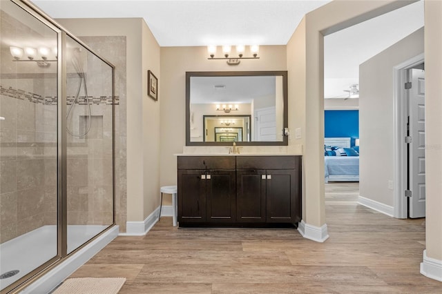 bathroom featuring walk in shower, vanity, wood-type flooring, and ceiling fan