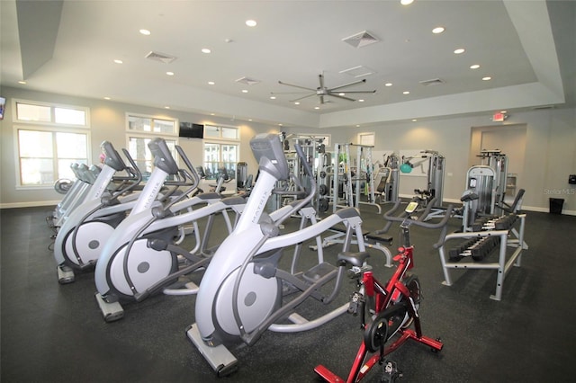 workout area featuring a tray ceiling and ceiling fan