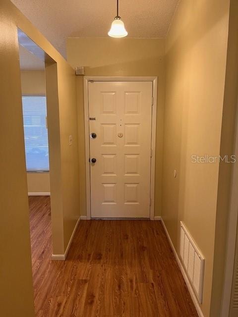 doorway to outside with a textured ceiling and dark wood-type flooring