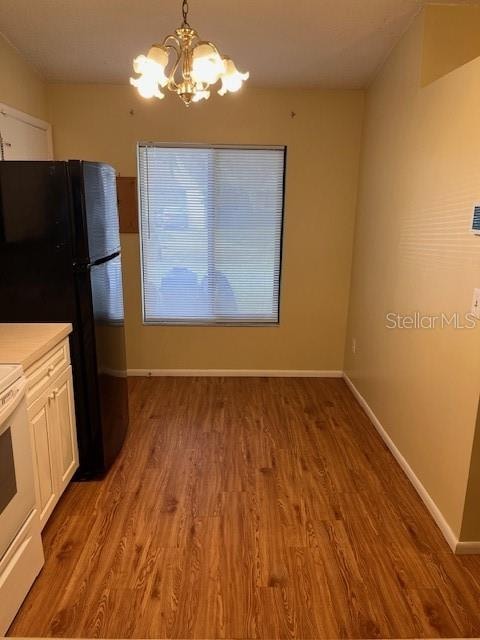 kitchen featuring hardwood / wood-style flooring, a notable chandelier, white cabinets, white range oven, and decorative light fixtures