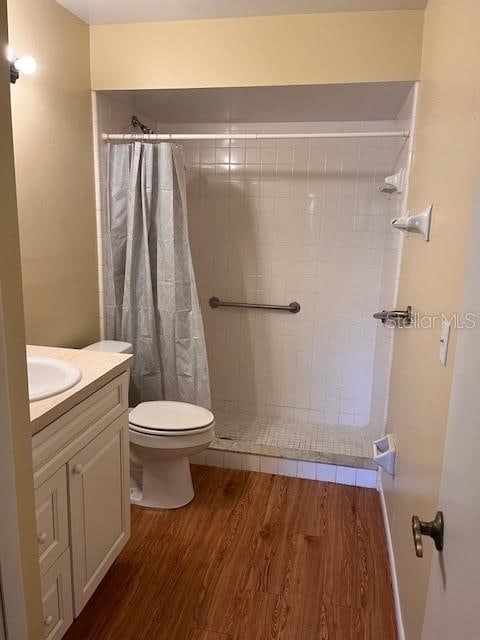 bathroom with wood-type flooring, walk in shower, vanity, and toilet