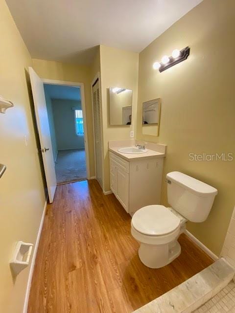 bathroom featuring wood-type flooring, vanity, and toilet