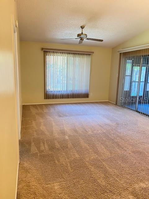 spare room with a textured ceiling, carpet flooring, and ceiling fan