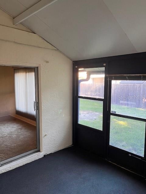 carpeted spare room featuring vaulted ceiling with beams