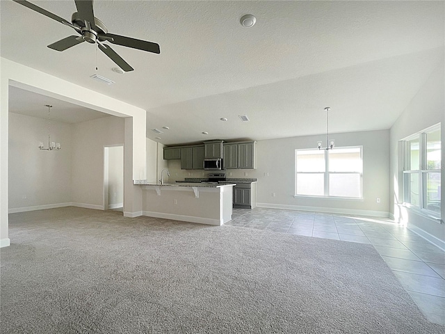 unfurnished living room featuring a textured ceiling, ceiling fan with notable chandelier, light tile patterned floors, and lofted ceiling