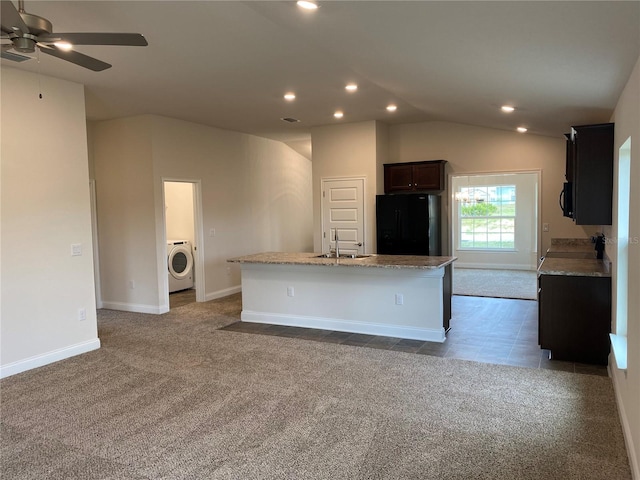 kitchen with an island with sink, lofted ceiling, sink, washer / dryer, and black refrigerator