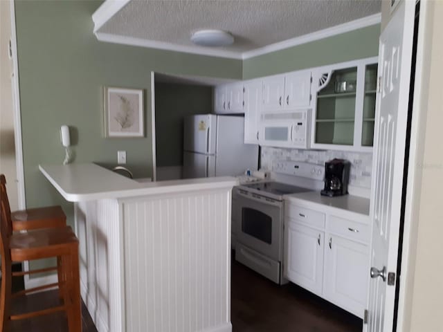 kitchen with white appliances, white cabinetry, a kitchen breakfast bar, kitchen peninsula, and a textured ceiling