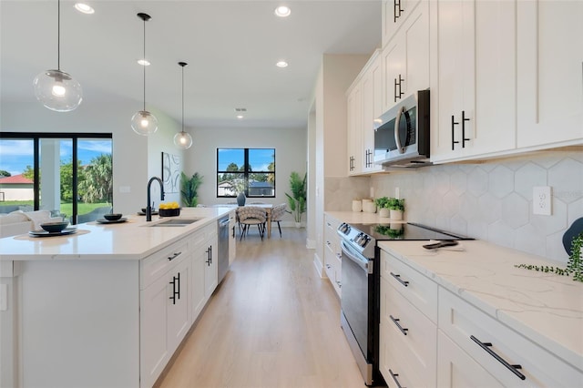 kitchen with appliances with stainless steel finishes, a kitchen island with sink, sink, and a wealth of natural light