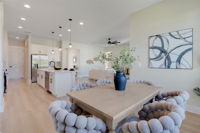 dining space with light wood-type flooring, ceiling fan, and sink