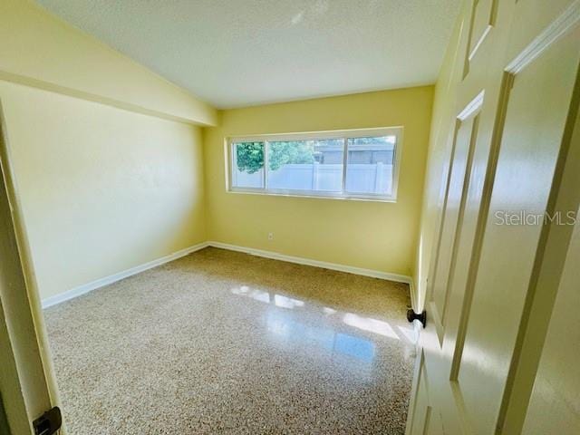 spare room with a textured ceiling and lofted ceiling