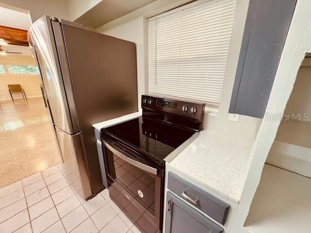 kitchen with gray cabinets, black range with electric stovetop, stainless steel fridge, and light tile patterned floors