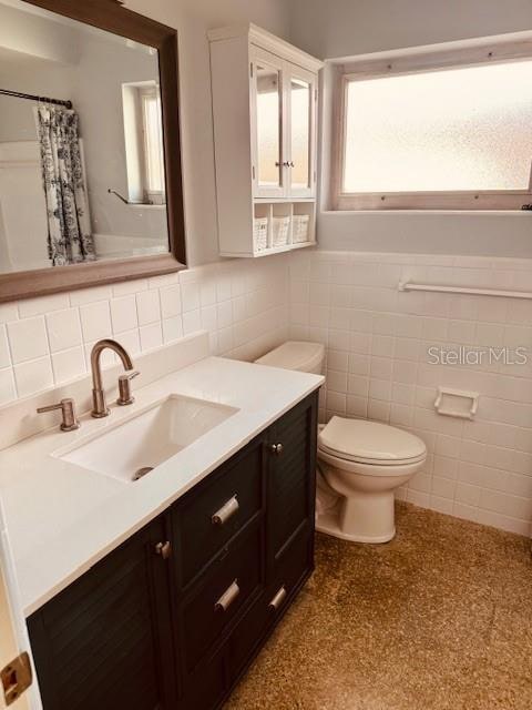 bathroom with tile walls, vanity, and toilet