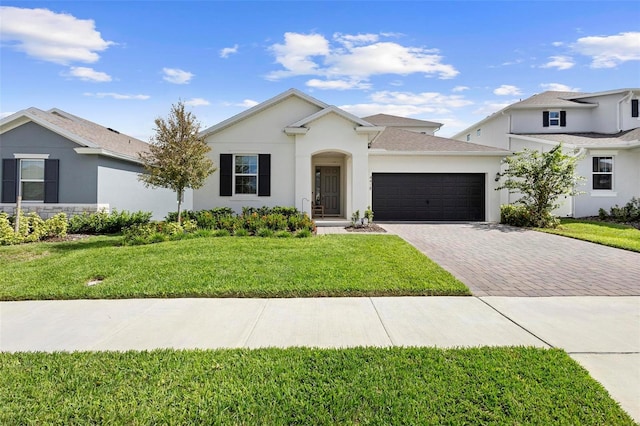 view of front of house featuring a garage, decorative driveway, a front yard, and stucco siding