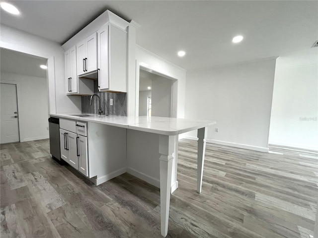 kitchen featuring white cabinetry, hardwood / wood-style flooring, sink, and a kitchen breakfast bar