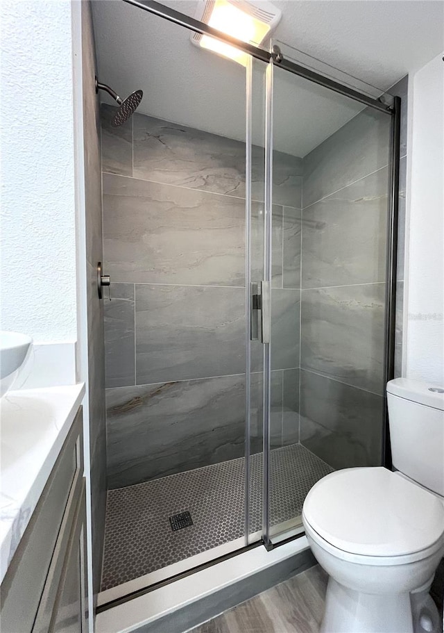 bathroom featuring wood-type flooring, vanity, toilet, and an enclosed shower