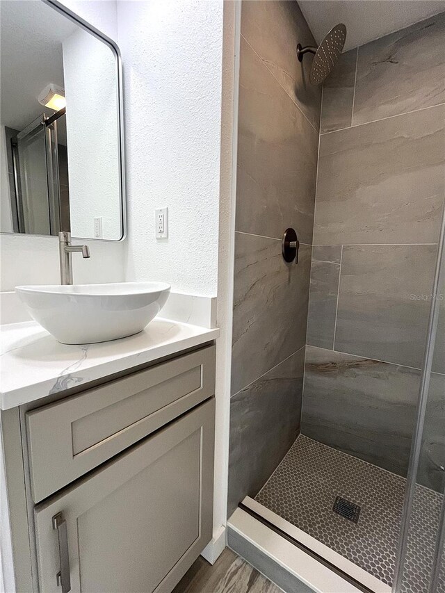 bathroom featuring vanity, wood-type flooring, and tiled shower