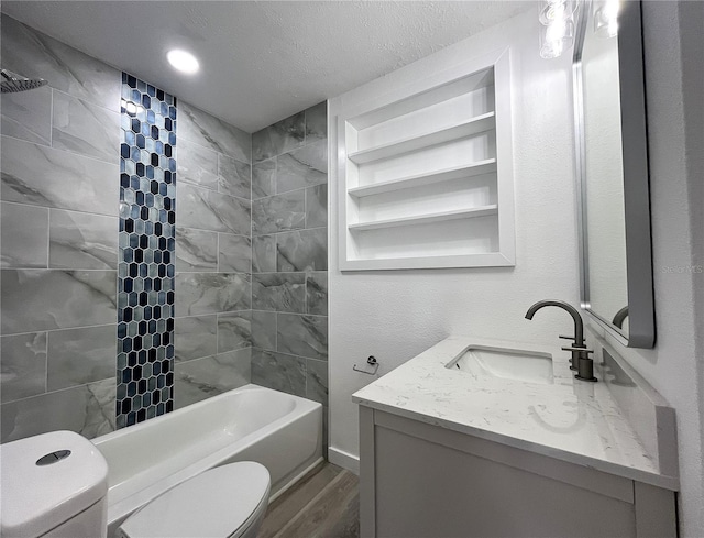 full bathroom with a textured ceiling, wood-type flooring, vanity, toilet, and tiled shower / bath combo