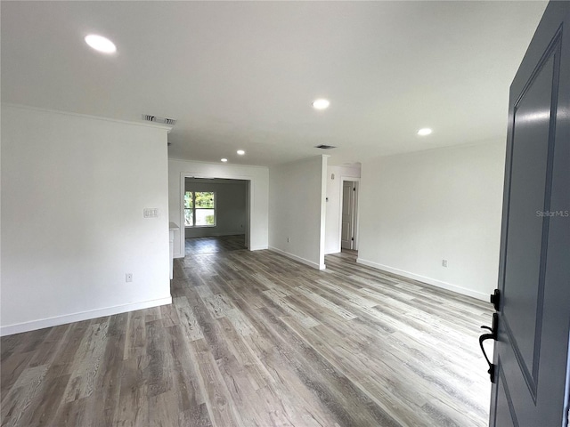 empty room featuring light wood-type flooring and crown molding