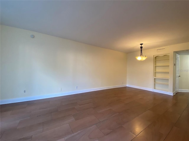 unfurnished room featuring built in shelves and dark hardwood / wood-style flooring